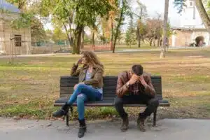 A stock photo showing a sad couple on a park bench.