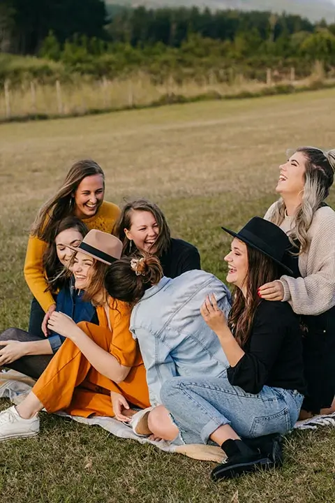 Anxiety Treatment 1 Group of women sitting on a blanket outdoors, laughing and enjoying each other's company.