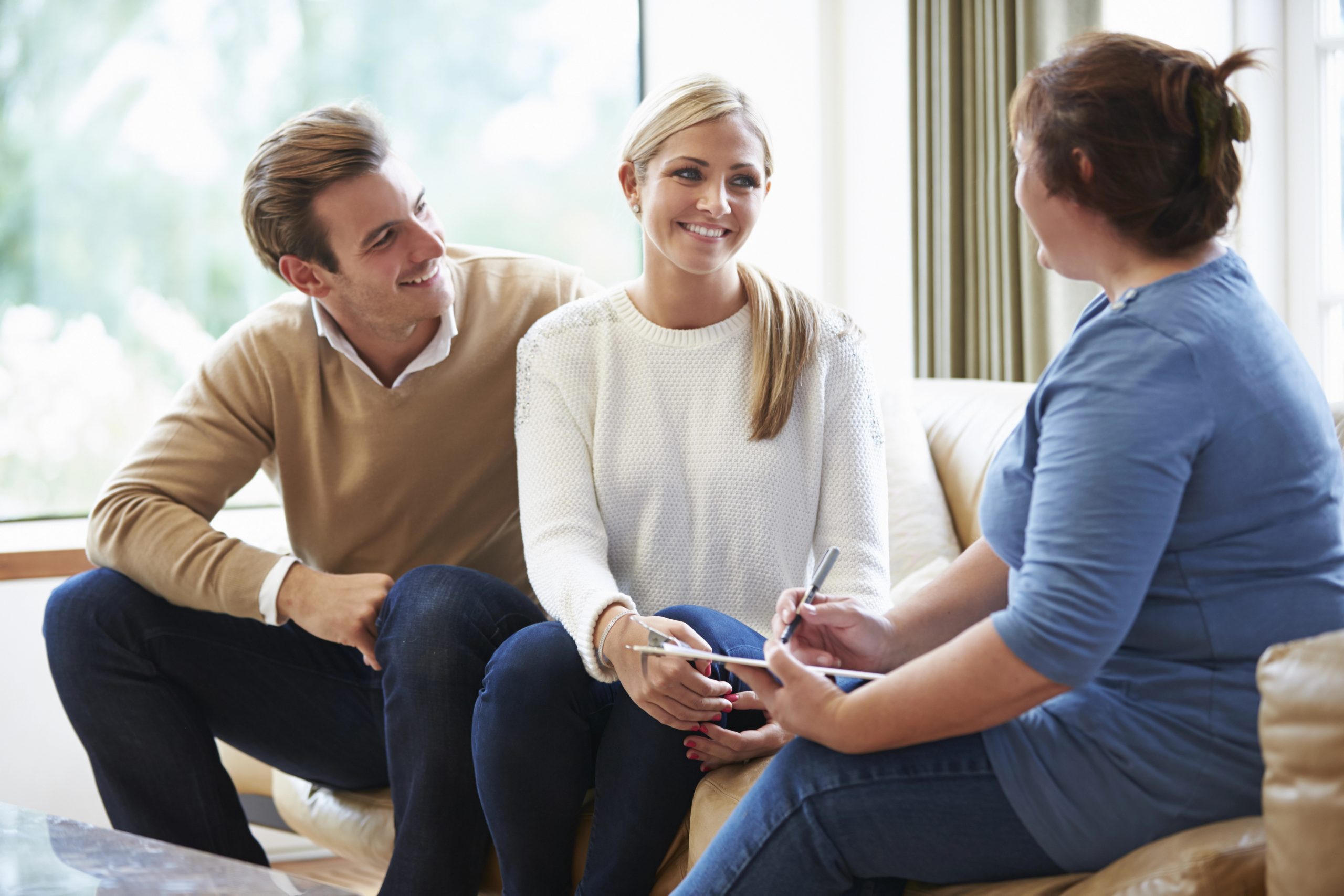 Couple speaking with a counselor during a therapy session, representing support and guidance through grief recovery.