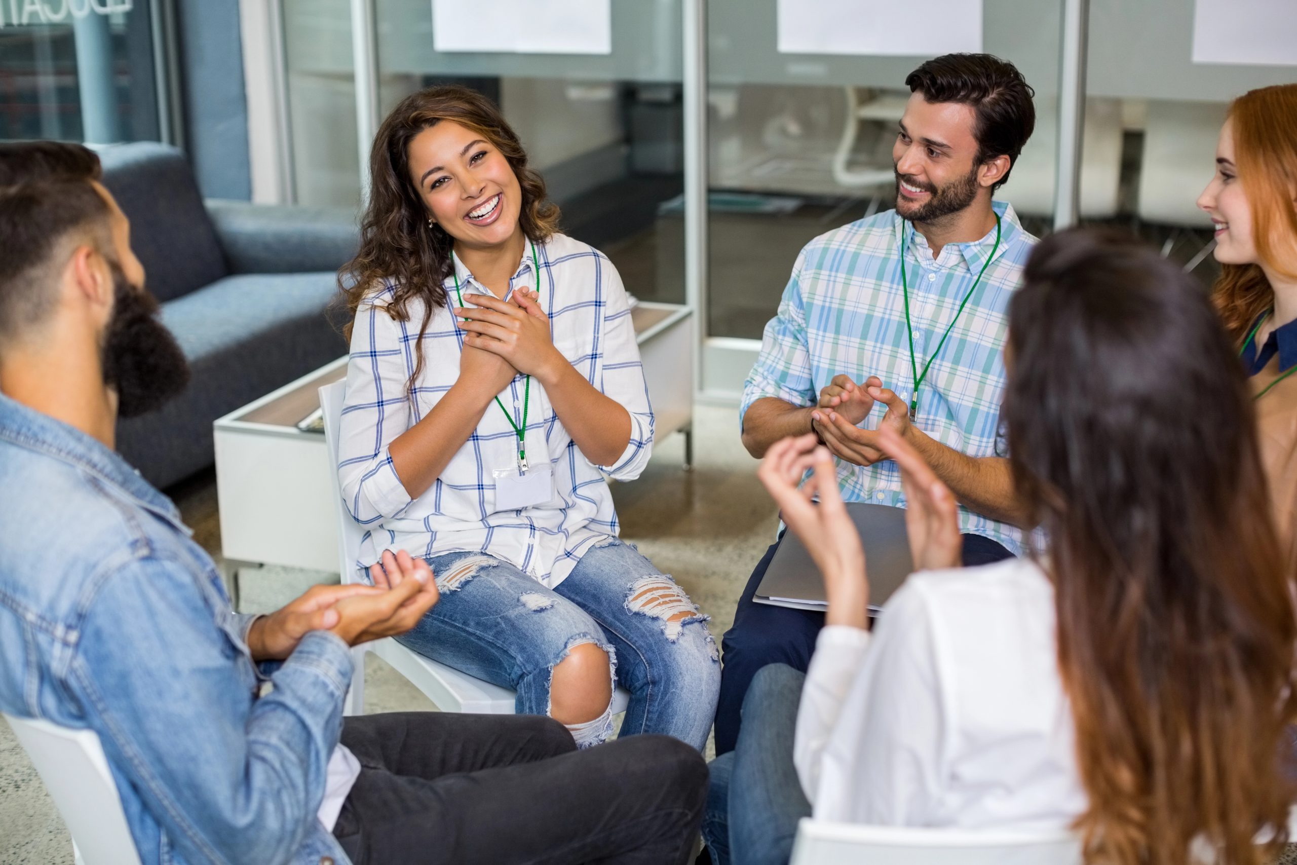 Woman smiling and sharing in a supportive group discussion.