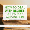 A graphic that reads "How To Deal With Regret: 5 Tips for Moving On" above a stock photo of a woman sitting on the beach at sunset staring at the water.