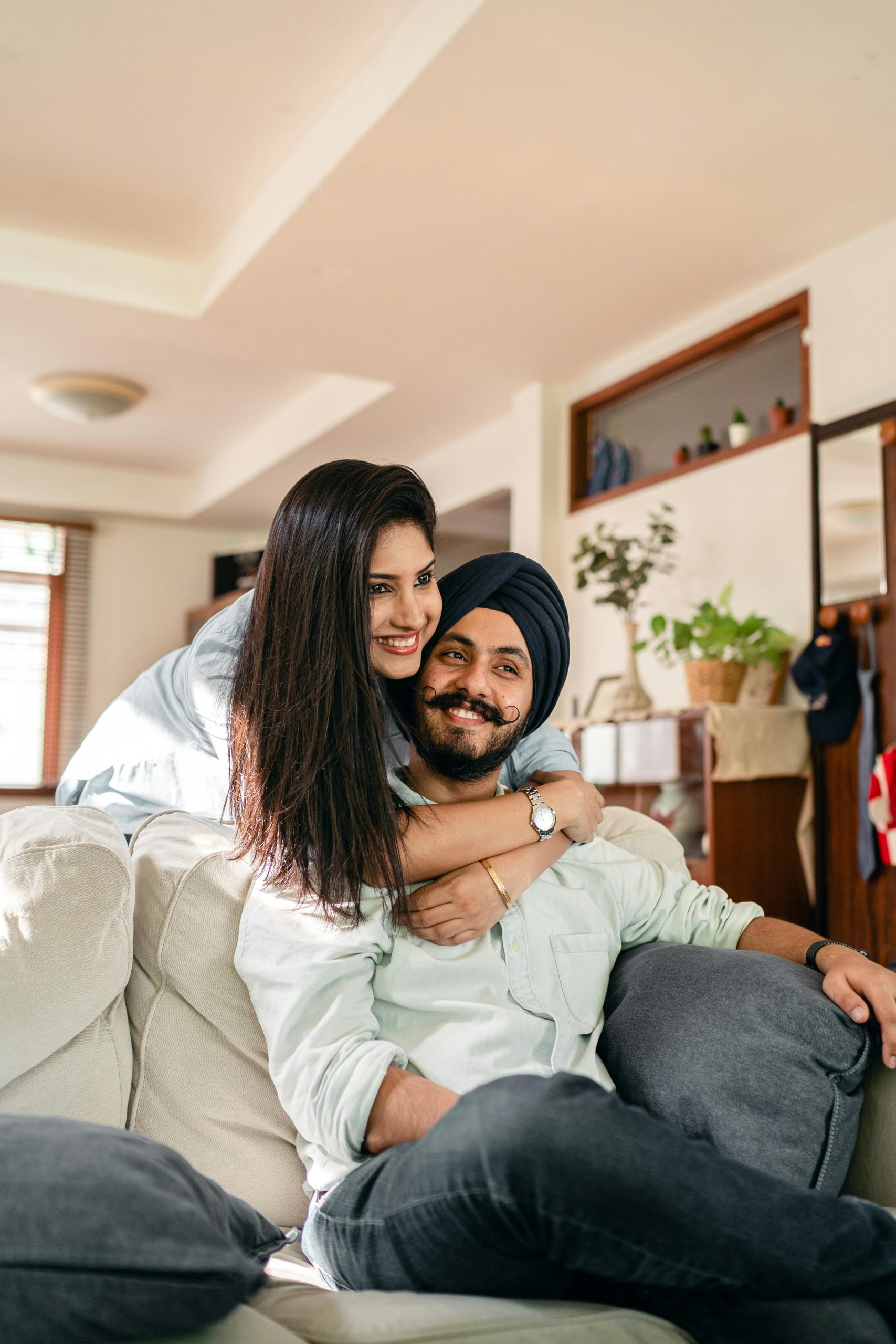 Smiling couple embracing on a couch, sharing a warm and supportive moment at home.