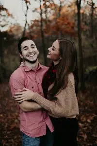 A stock photo showing a smiling couple standing outside in the fall. 