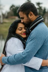 An Indian couple hugging and smiling outdoors.